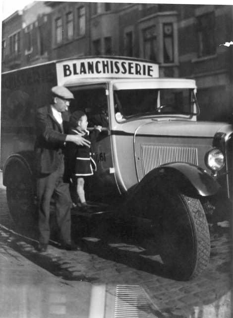 Archieffoto: een bestelwagen van de wasserij met zijn chauffeur, in een Brusselse straat met kasseien