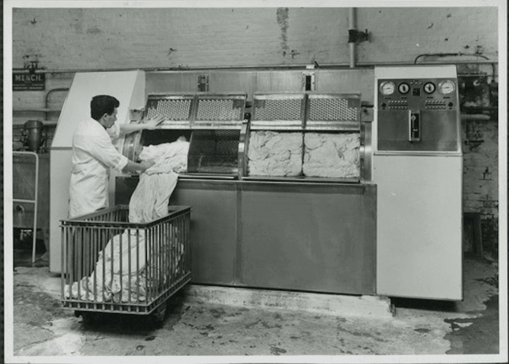 Een arbeider laadt een industriële trommelwasmachine in het atelier