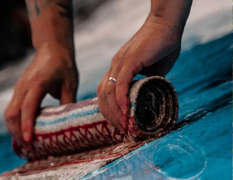 A rug being rolled by hand on the flat washing table